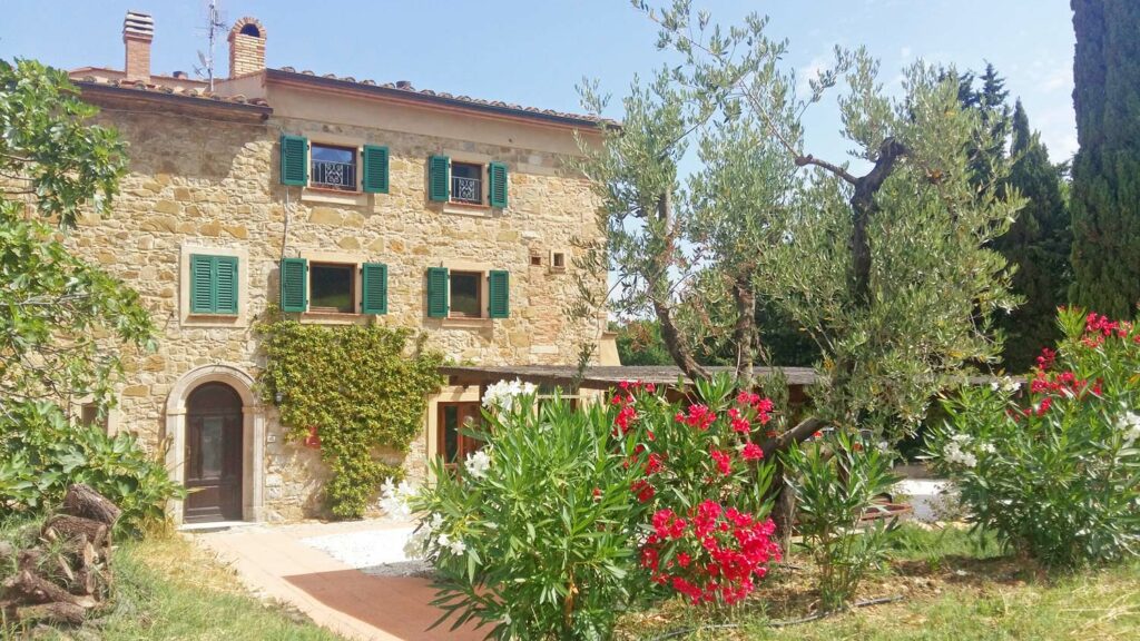 Große, italienische Finca mit Steinwänden und grünen Fensterläden mit schön begrünter Außenanlage
